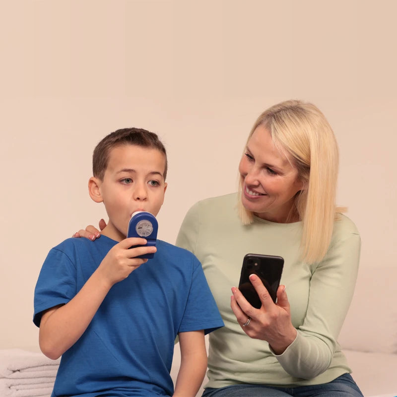 Safey Clinic Spirometer Lite with a little kid in a blue shirt taking a test with his mum smiling at him. Shop now at Zone Medical.